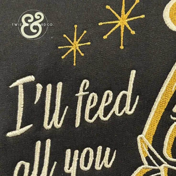 Embroidered text 'I'll feed all you' with golden star designs on black fabric by Twist & Thread Co.