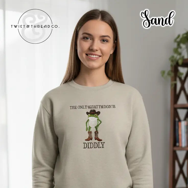 Young woman wearing sand-colored sweatshirt with cartoon frog in cowboy hat and boots, text design