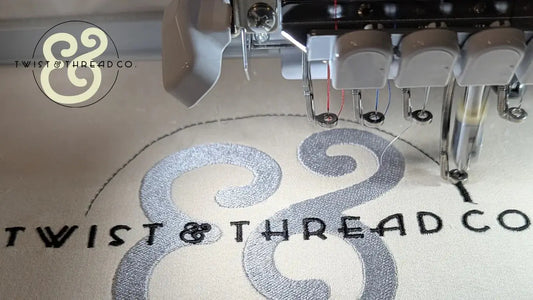 Embroidery machine stitching Twist & Thread Co. logo on fabric, premium custom apparel