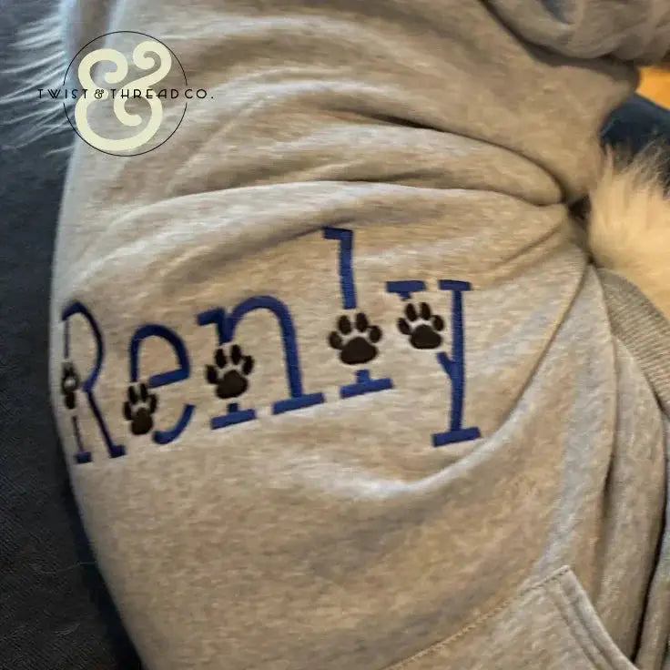 Gray custom embroidered pet hoodie with blue paw print design and 'Renly' text, Twist & Thread Co.