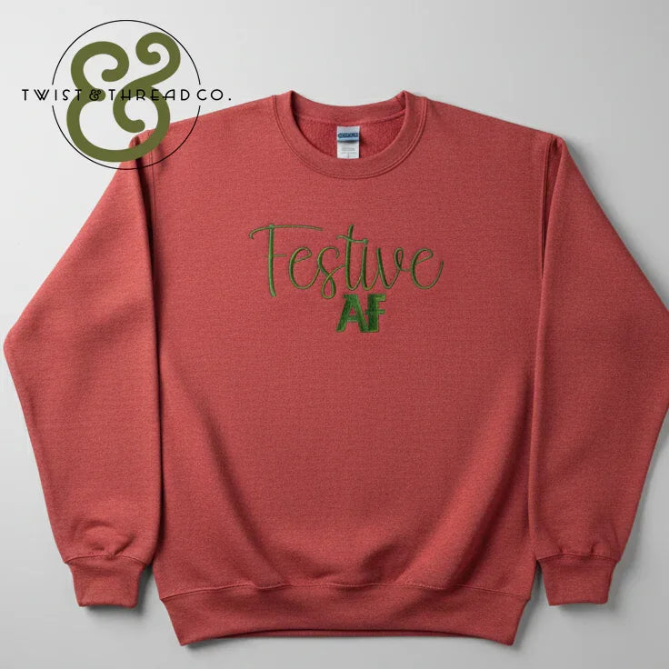 Red crewneck sweatshirt with green embroidered text "Festive AF" and Twist & Thread Co. logo