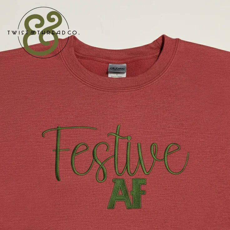 Red Gildan t-shirt with green embroidered text 'Festive AF' and Twist & Thread Co. logo