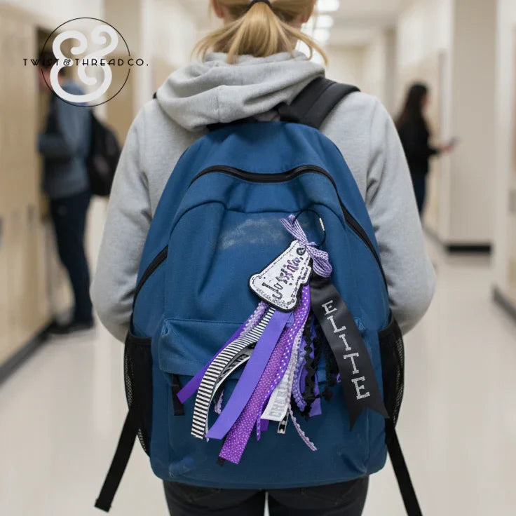 Blue backpack with custom bag tag and purple ribbons in a school hallway