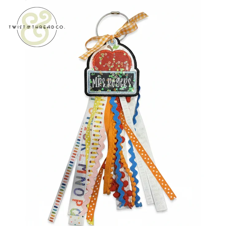 Teacher bag tag with apple design, Mrs Rogers name, and colorful ribbons with patterns