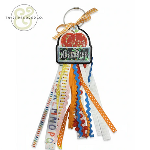 Teacher bag tag with apple design, Mrs Rogers name, and colorful ribbons with patterns