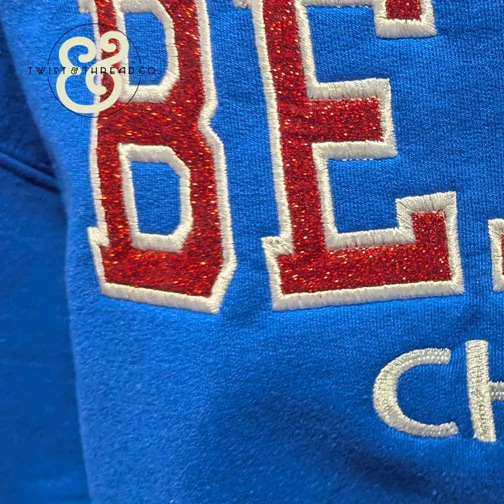 Red and white embroidered applique letters on blue fabric, Twist & Thread Co. apparel detail