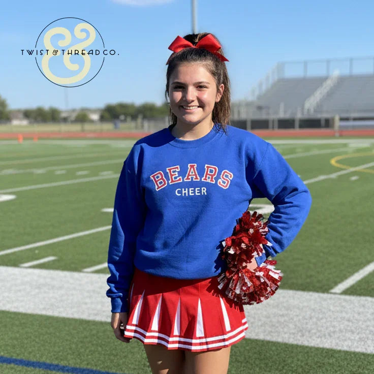 Cheerleader in blue Bears Cheer sweatshirt and red skirt on football field, Twist & Thread Co. apparel