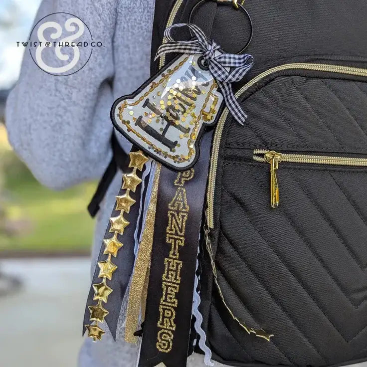 Black backpack with gold and black 'PANTHERS' bag tag featuring stars and ribbon accents
