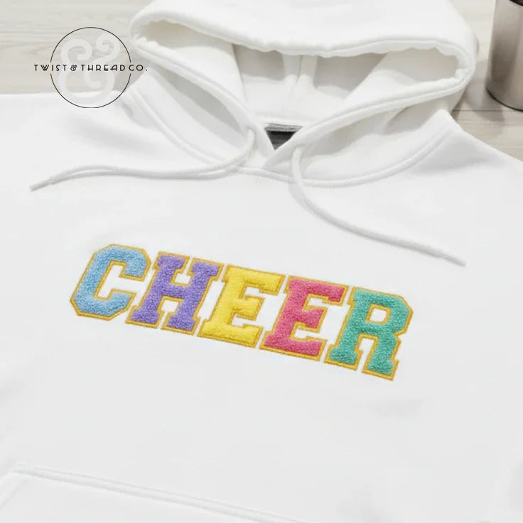 White hoodie with colorful embroidered CHEER text, Twist & Thread Co. branding visible