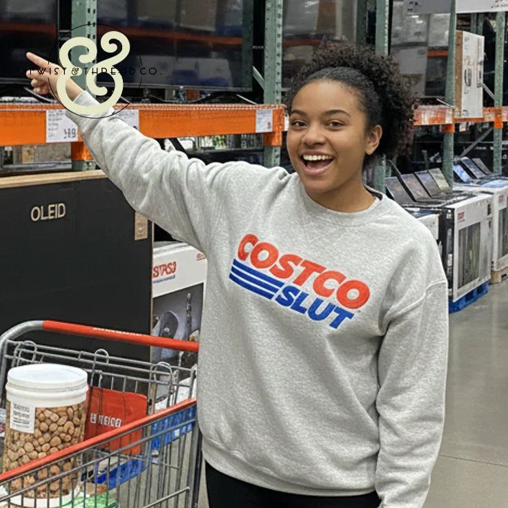 Smiling woman in a custom embroidered Costco-themed sweatshirt shopping in a warehouse.