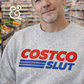 Person in gray custom embroidered hoodie with bold novelty text, standing in a store aisle.
