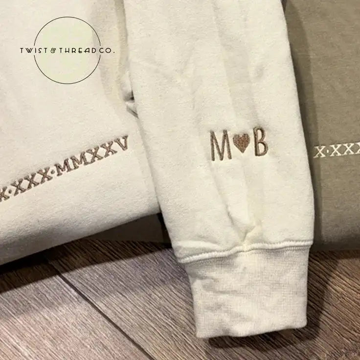 Custom embroidered beige sleeve with M heart B and Roman numerals, Twist & Thread Co. apparel