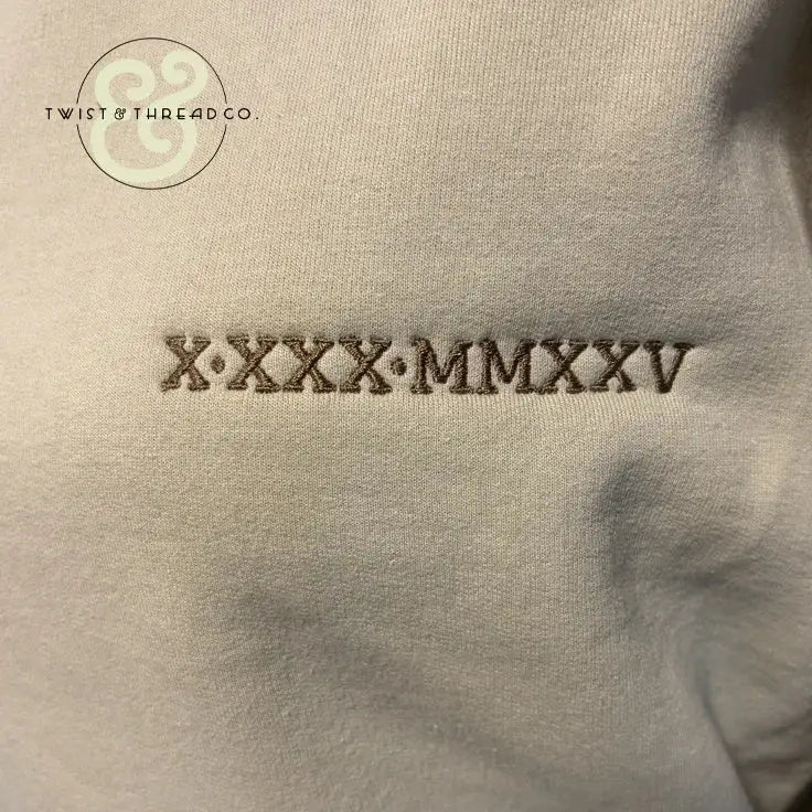 Embroidered Roman numerals on beige fabric, Twist & Thread Co. premium custom apparel.