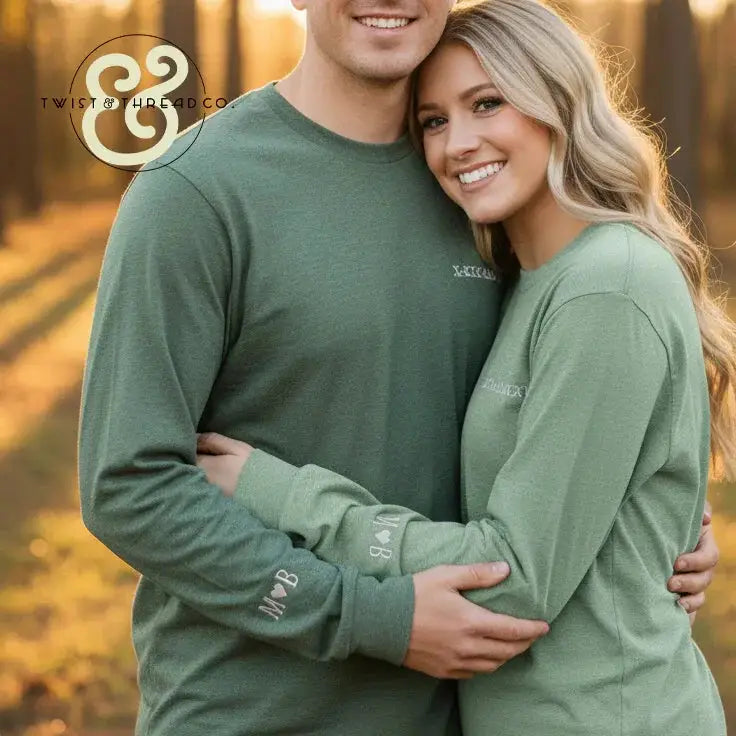 Smiling couple wearing matching green embroidered sweatshirts from Twist & Thread Co. outdoors