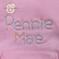 Pink fabric with embroidered floral text reading Penny Mae, premium custom thread work