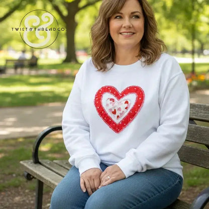 Woman wearing white sweatshirt with red heart applique by Twist & Thread Co. in park setting