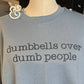 Light blue shirt with embroidered text saying dumbbells over dumb people fitness slogan