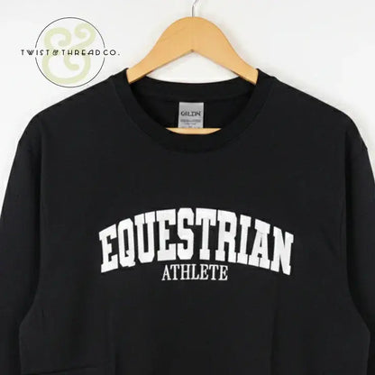 Black Gildan sweatshirt with white embroidered text 'EQUESTRIAN ATHLETE' hanging on wooden hanger