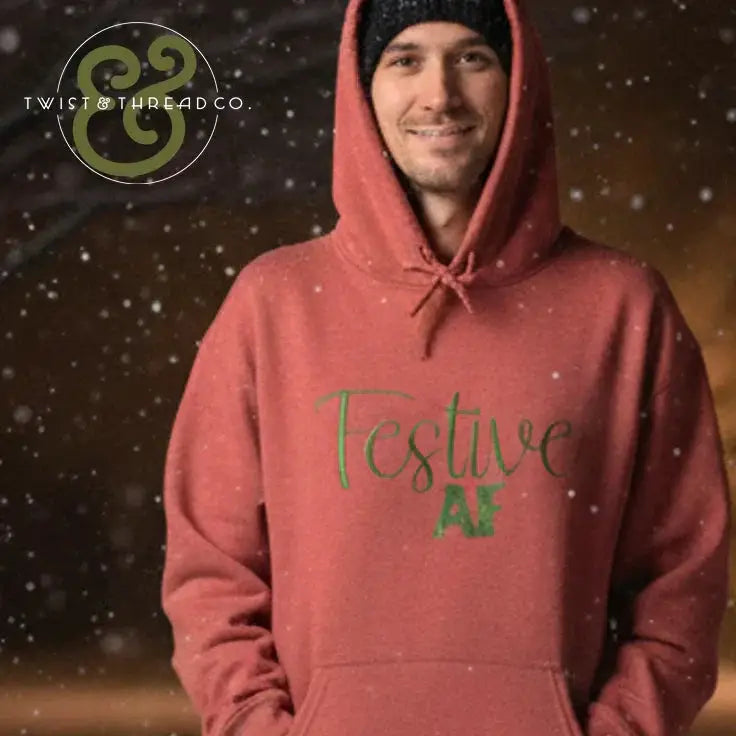 Man wearing red hoodie with green 'Festive AF' text, snowy winter scene background