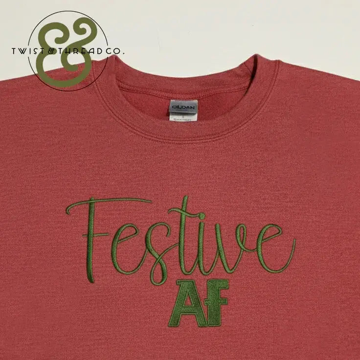 Red Gildan t-shirt with green embroidered text 'Festive AF' and Twist & Thread Co. logo
