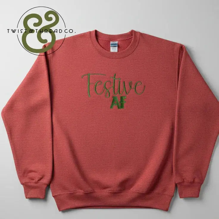 Red crewneck sweatshirt with green embroidered text "Festive AF" and Twist & Thread Co. logo