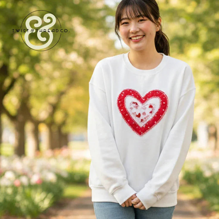 Woman wearing white sweatshirt with red heart applique, Twist & Thread Co. embroidered apparel