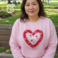 Woman wearing a pink heart applique embroidered sweatshirt by Twist & Thread Co. in park
