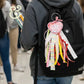 Black backpack with colorful embroidered heart-shaped accessory and ribbon, Twist & Thread Co.