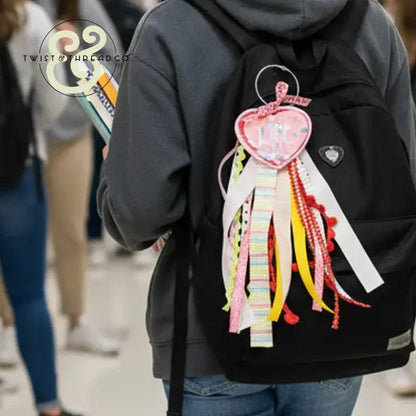 Black backpack with colorful embroidered heart-shaped accessory and ribbon, Twist & Thread Co.