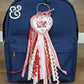 Embroidered heart-shaped 'Love' keychain with pink and red ribbons on navy backpack from Twist & Thread Co.