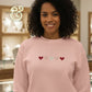 Woman wearing pink embroidered sweatshirt with four heart designs by Twist & Thread Co.
