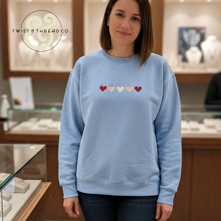 Woman wearing light blue embroidered sweatshirt with hearts, Twist & Thread Co. apparel