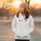 Woman wearing a white hoodie with embroidered hearts, Twist & Thread Co. apparel outdoors