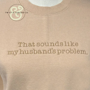 Beige sweatshirt with embroidered text that reads 'That sounds like my husband's problem' and Twist & Thread Co. logo
