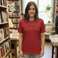 Smiling woman wearing red T-shirt with text 'I read past my bedtime' in cozy bookstore setting
