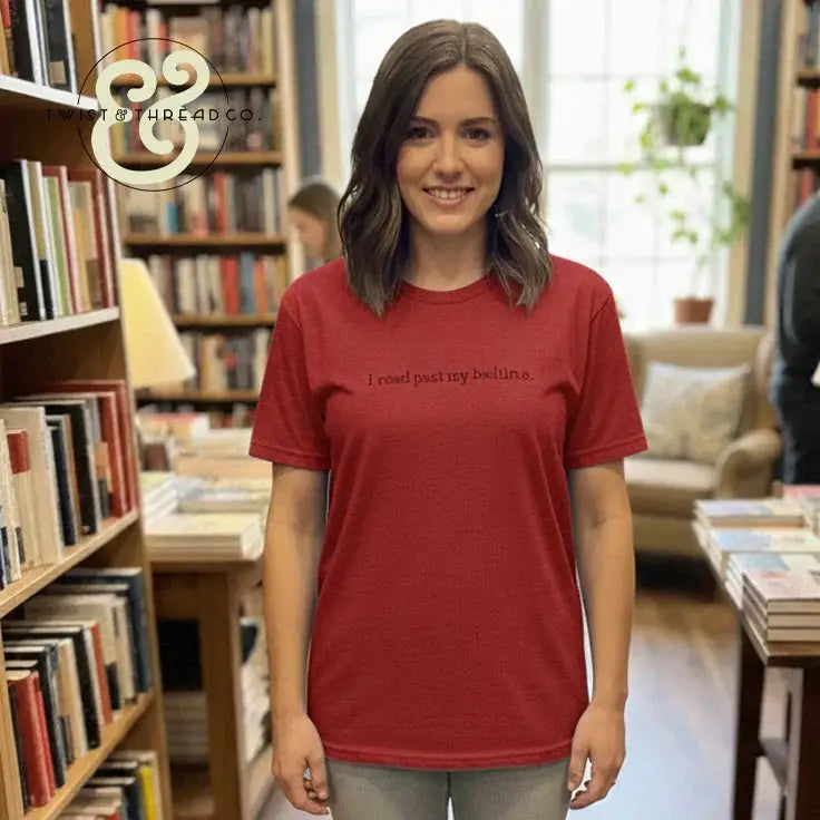 Smiling woman wearing red T-shirt with text 'I read past my bedtime' in cozy bookstore setting