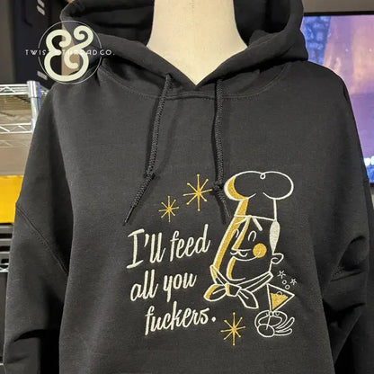 Black hoodie with embroidered chef cartoon and text I'll feed all you fuckers in white and gold