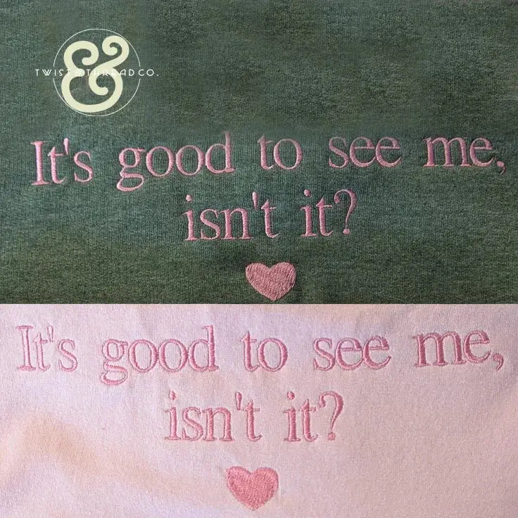 Green and pink fabric embroidery with the phrase "It's good to see me, isn't it?" and a small heart