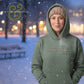 Woman wearing green hoodie and knit hat in snowy park at night with blurred lights, Twist & Thread Co. logo