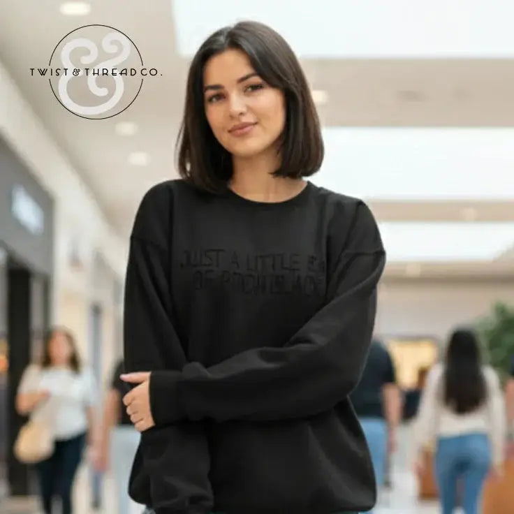 Young woman wearing black sweatshirt with embossed text, standing in indoor shopping mall