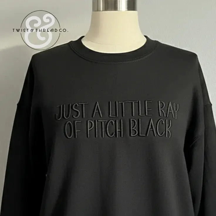 Black sweatshirt with embossed text Just a Little Ray of Pitch Black displayed on mannequin