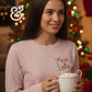 Woman in Merry & Bright Christmas sweatshirt holding hot cocoa with candy cane by Christmas tree