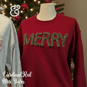 Cardinal red Christmas sweater with green yarn MERRY text, holiday tree in background