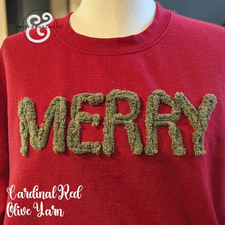 Red sweatshirt with fuzzy olive yarn letters spelling MERRY on a mannequin