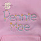 Pink fabric with embroidered floral text reading Penny Mae, premium custom thread work