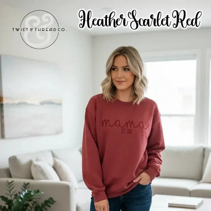 Woman wearing heather scarlet red "mama EST. 2012" sweatshirt in bright living room with white couch