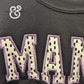 Black fabric with appliqué letters spelling 'MAM' in cream with black spots and purple stitching