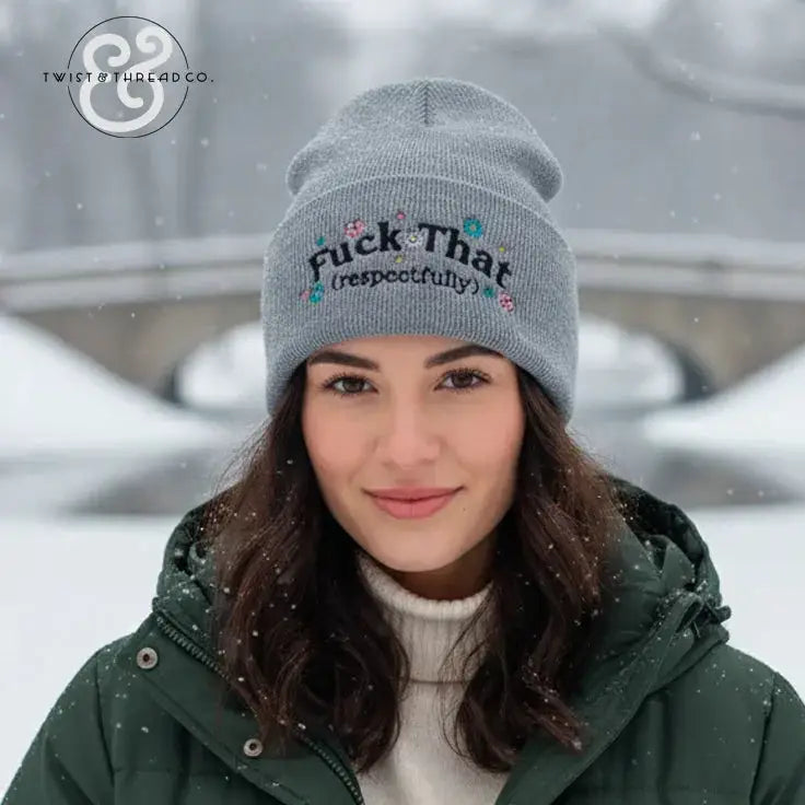 Woman in gray embroidered winter hat with text, outdoors in snowy setting