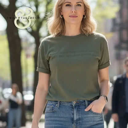 Woman wearing green graphic tee and blue jeans standing outdoors in city street with trees