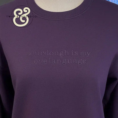 Purple sweatshirt with embossed text 'sourdough is my lovelanguage' on chest